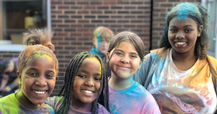 Four young people at YMCA North Staffordshire enjoying a colour run dash. They are covered in rainbow colours and smiling.