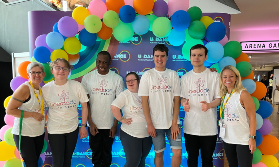 Group of young people posing for a photo in front of balloons. The young people have taken part in an event called U Dance.