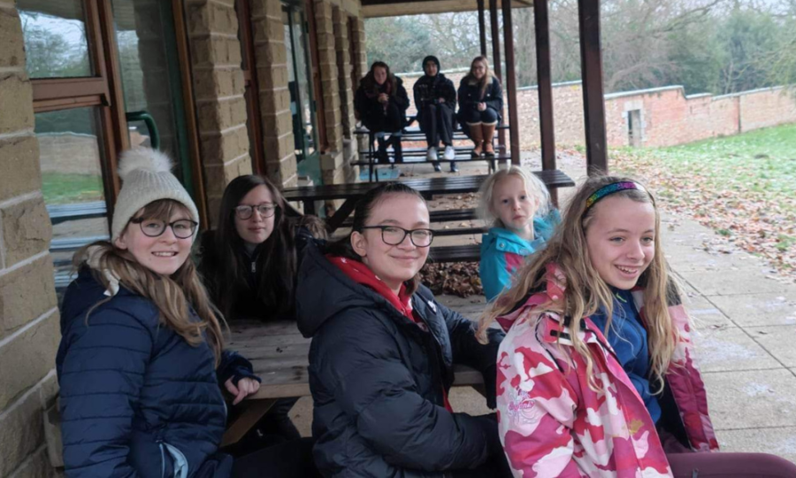 Young people are seated looking out over the Whiteley Woods outdoor adventure space. They are smiling.