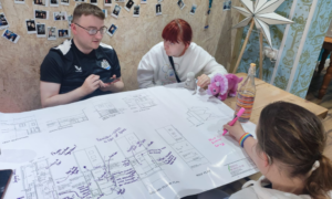 Three young people are looking at plans for their new youth hub. They are talking and adding their ideas.